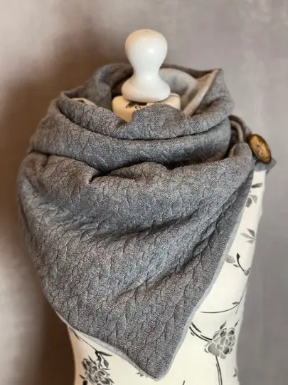 Grauer Wickelschal als Dreieckstuch, einfaches Accessoire, zeigt die weiche Stoffstruktur und den stilvollen Schnitt.
